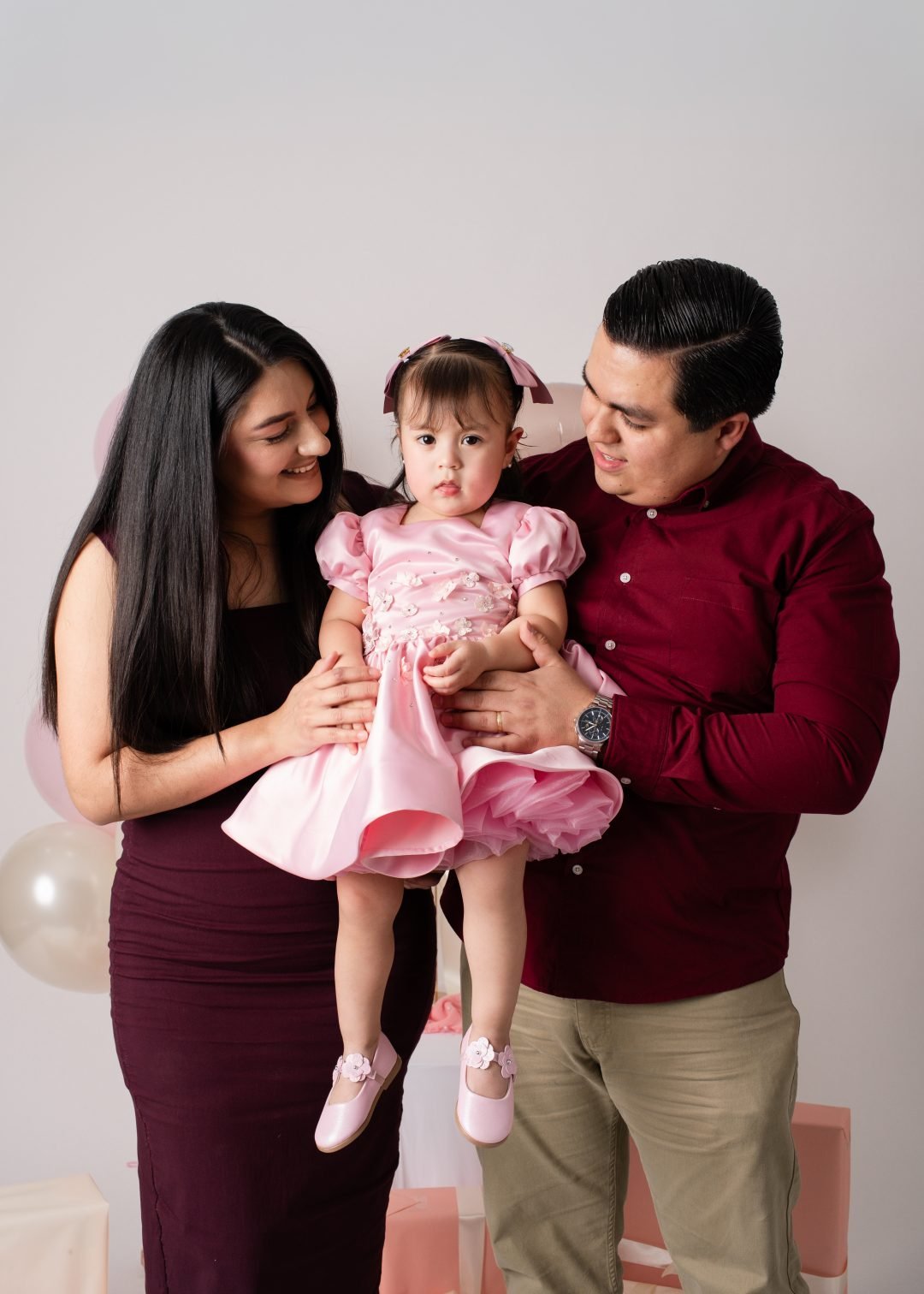 familia posando con globos color vino en sesión de primer año