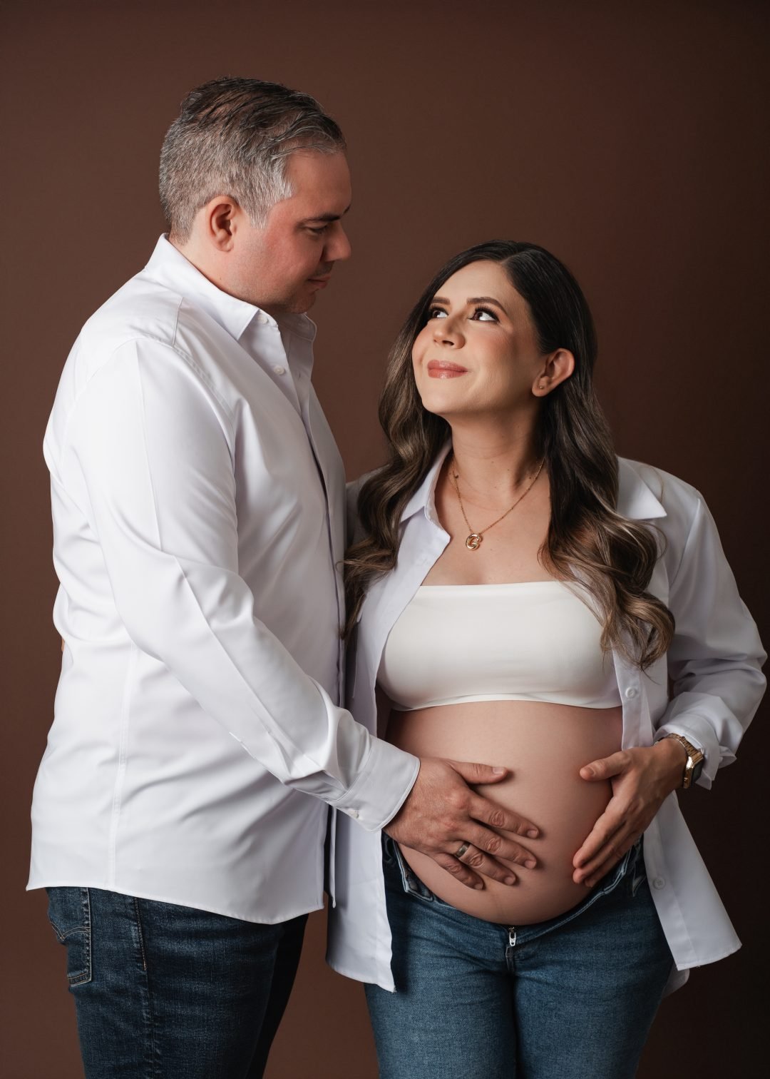 pareja esperando bebé con las manos juntas sobre el vientre