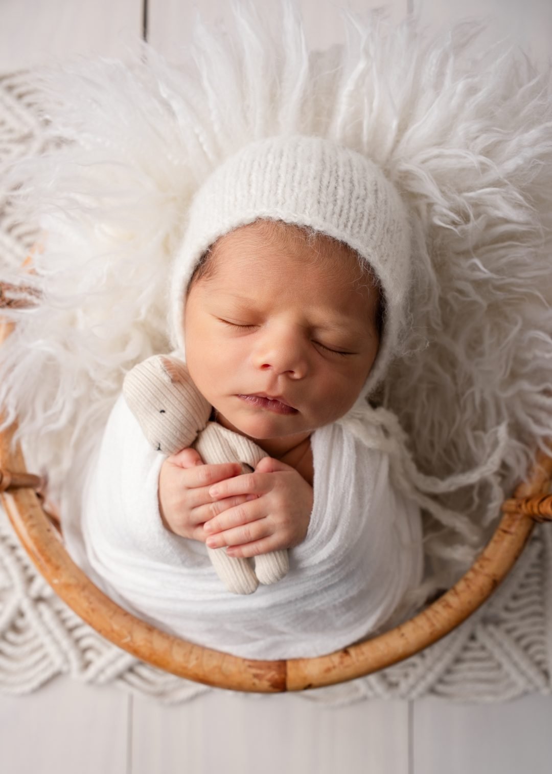 recién nacido con gorro tejido dormido en canasta con piel blanca