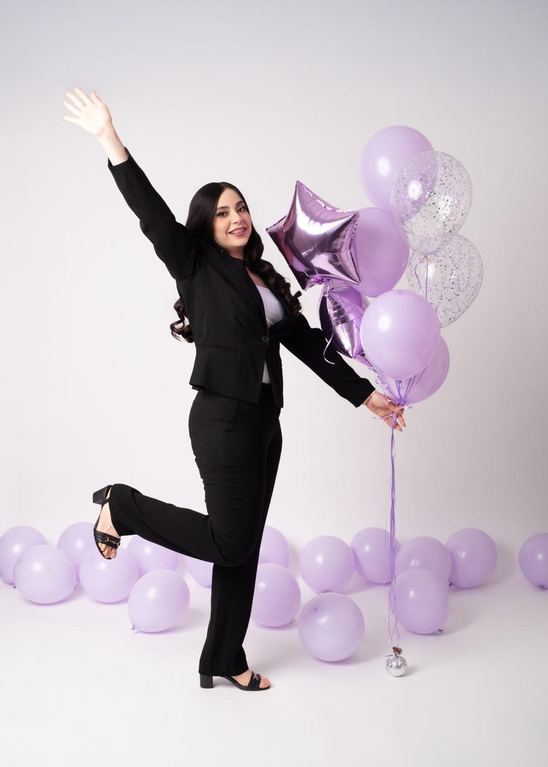 mujer celebrando con confeti y globos morados en su cumpleaños