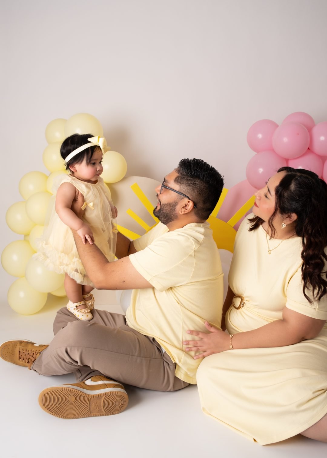 familia sentada en el piso jugando con su bebé y globos