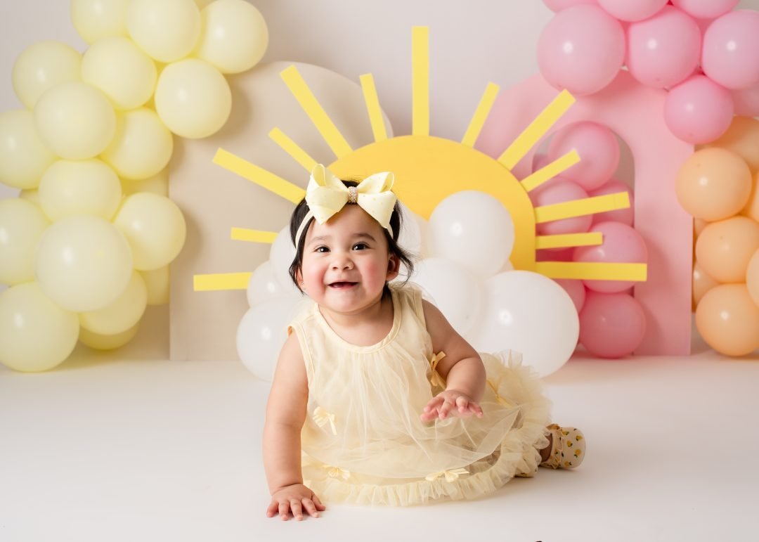 niña sonriente frente a decoración de sol con globos